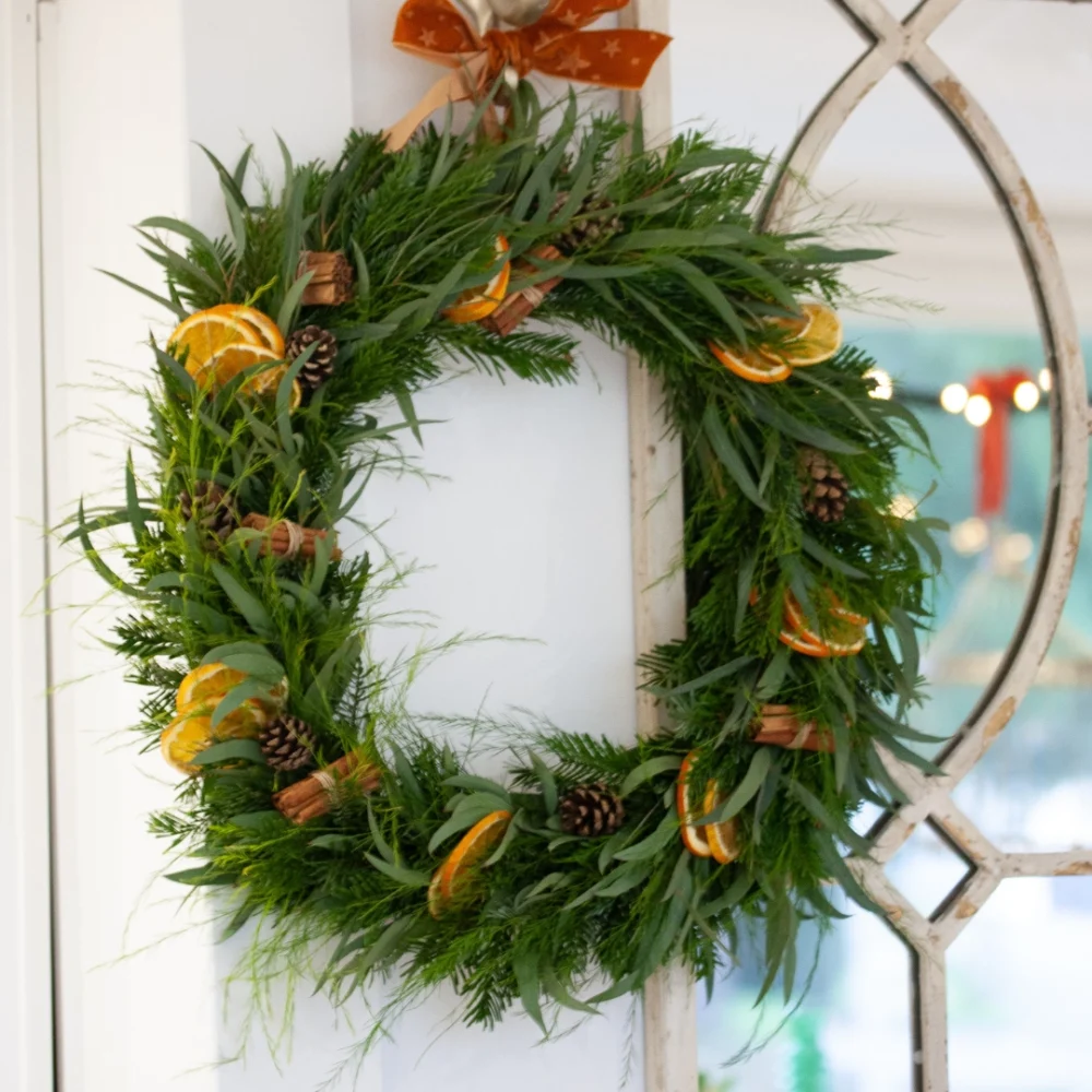 Couronne de Noël réalisé avec du sapin, de l'eucalyptus, du tree fern et des élements naturels (orange, cannelle, pommes de pin)